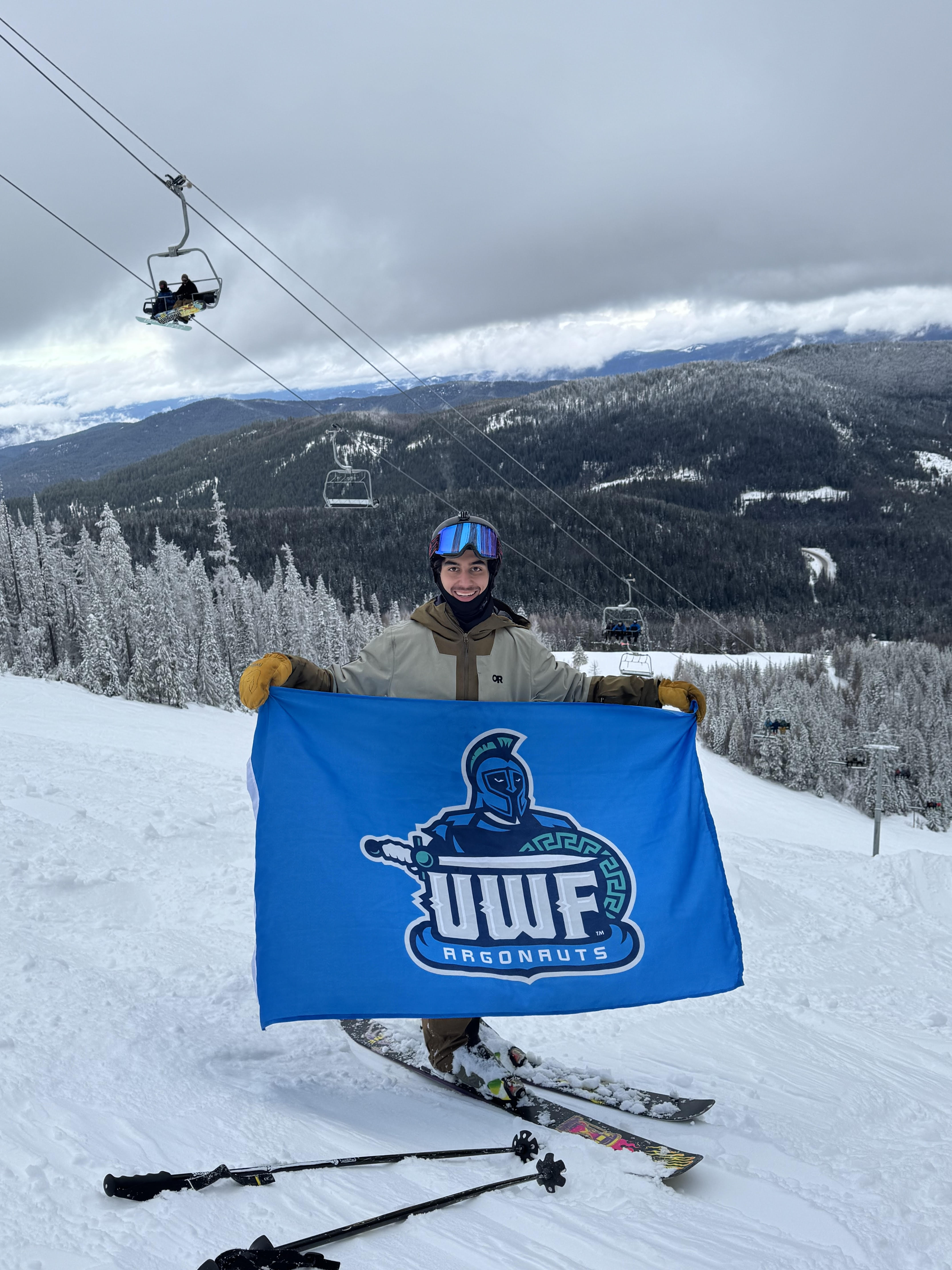 Skiing with UWF Argonauts flag on snowy mountain